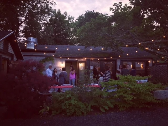 Guests gathered under string lights on the patio at dusk for a Thursday night party.