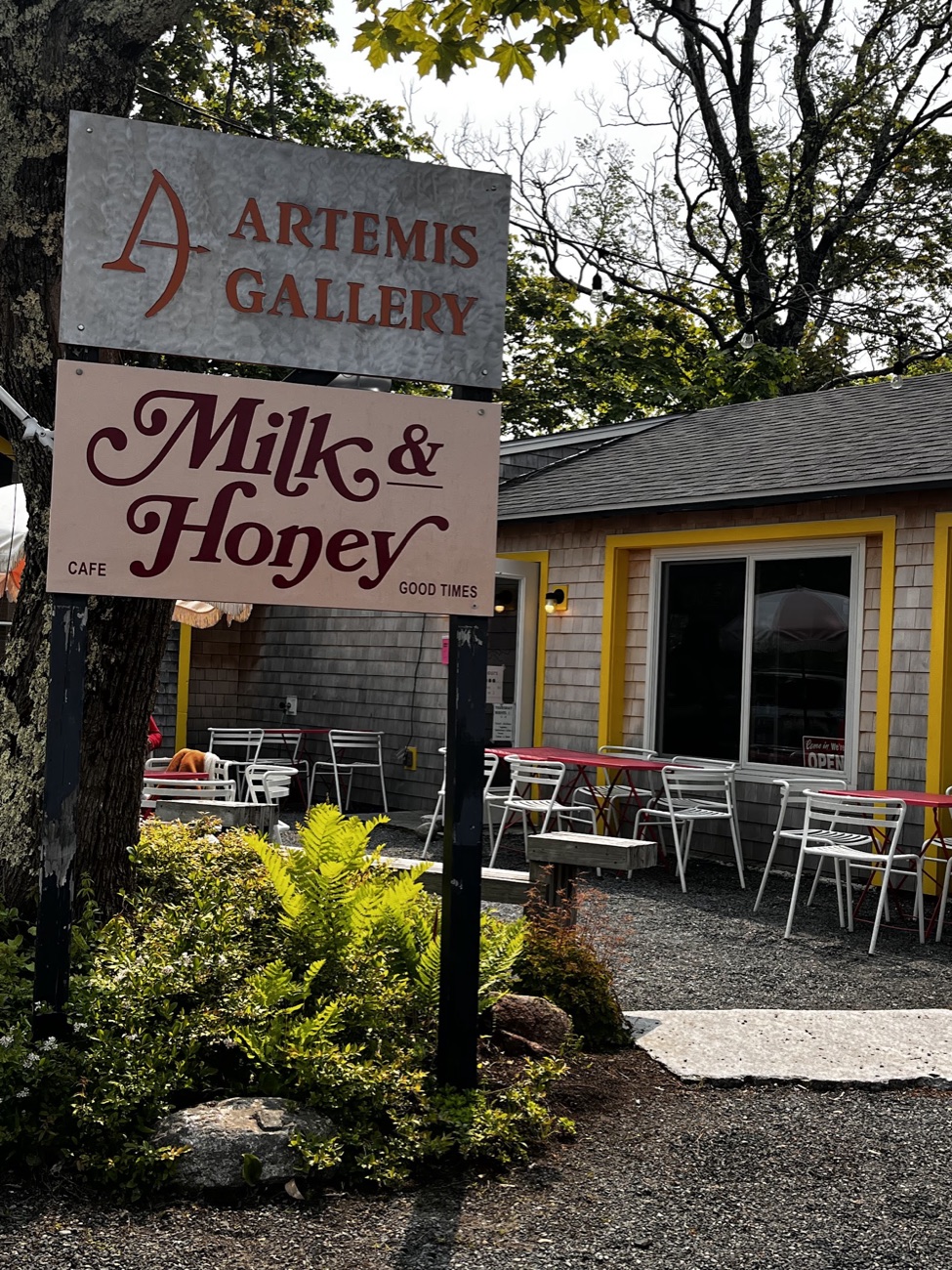 The hand-painted Milk & Honey sign out front — ‘Café · Good Times’ — beside the café’s grey-shingled porch.